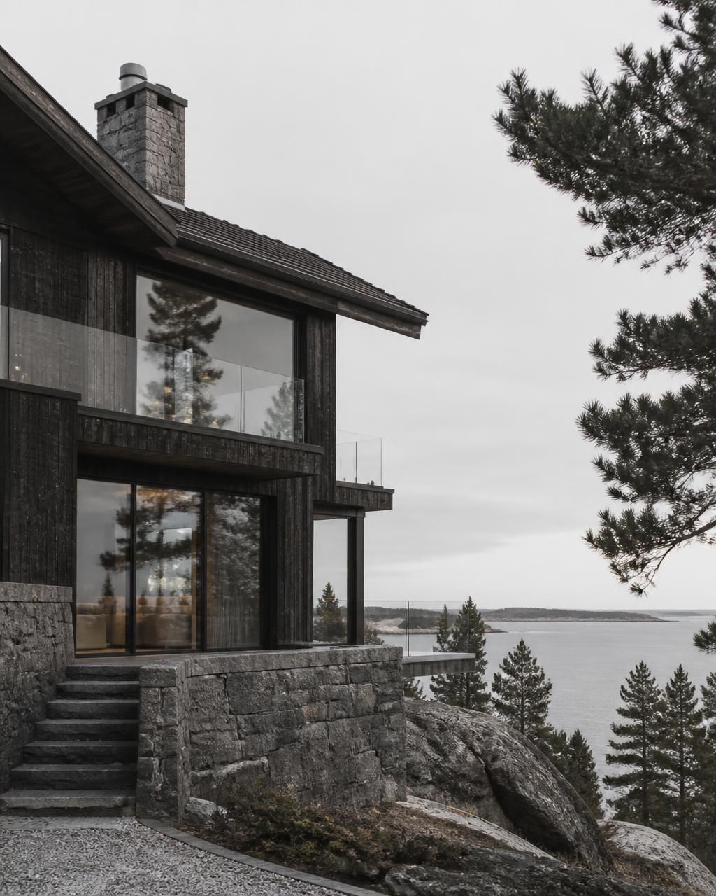 A dark-timber and stone coastal residence above the sea in low winter light